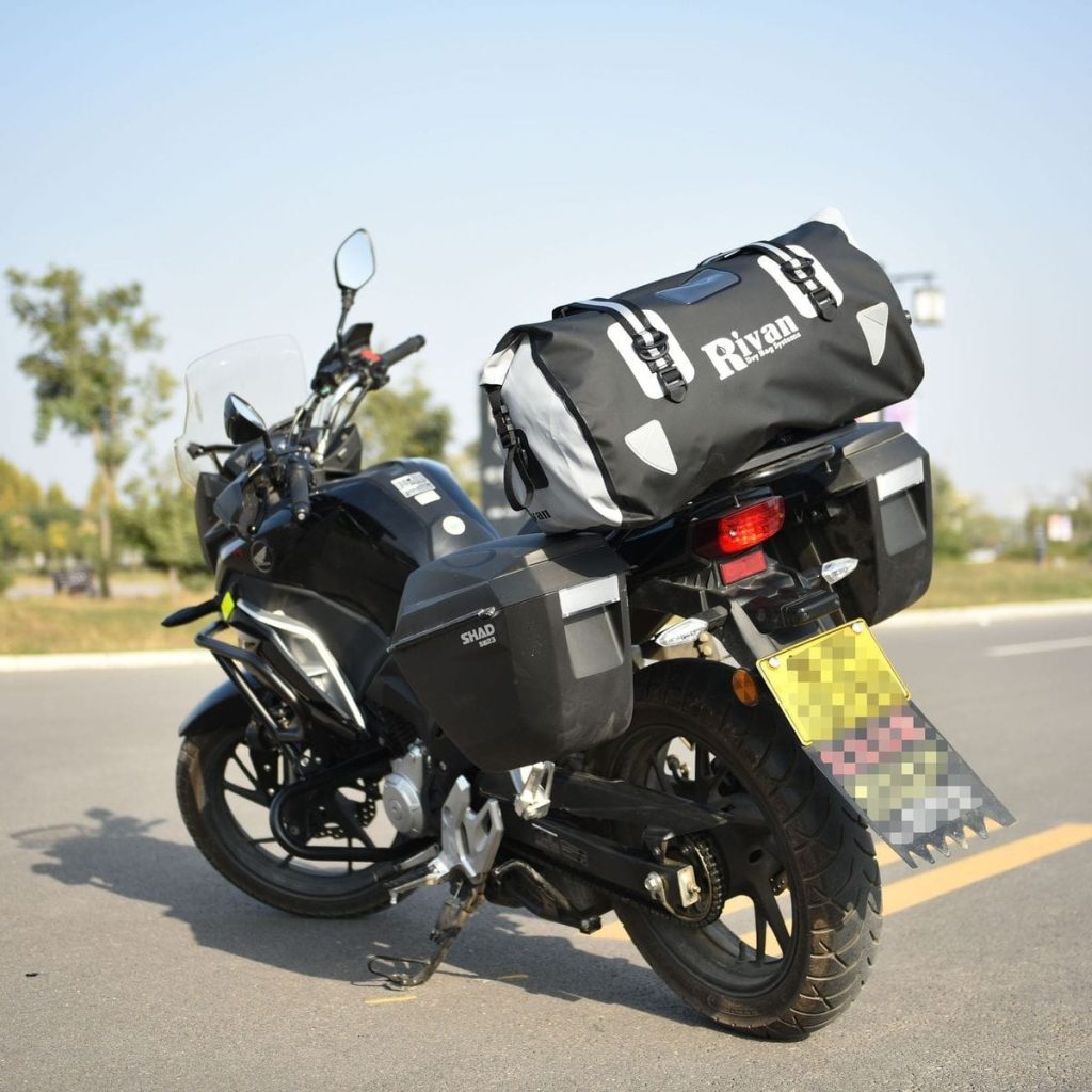 Sac étanche moto 60L Rivan, PVC noir et gris, fermeture par enroulement, vue trois quarts sur moto